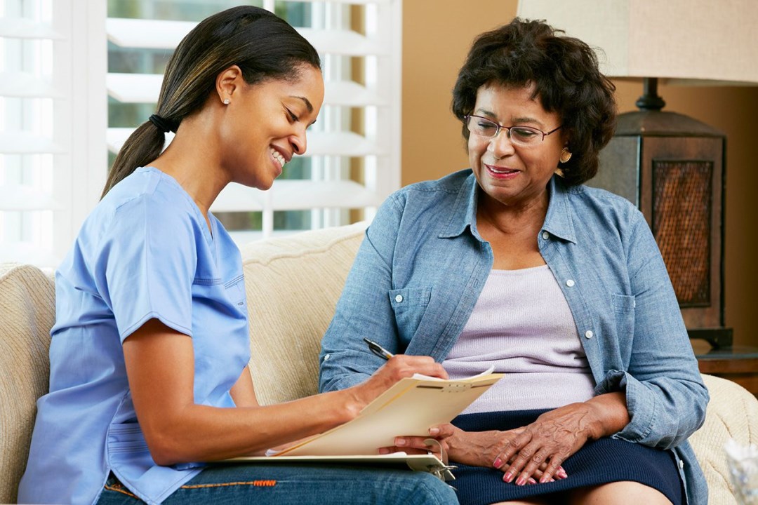 nurse-making-notes-during-home-visit-with-senior-female-patient